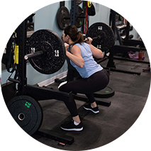  A member using the squat rack and a bar on her back