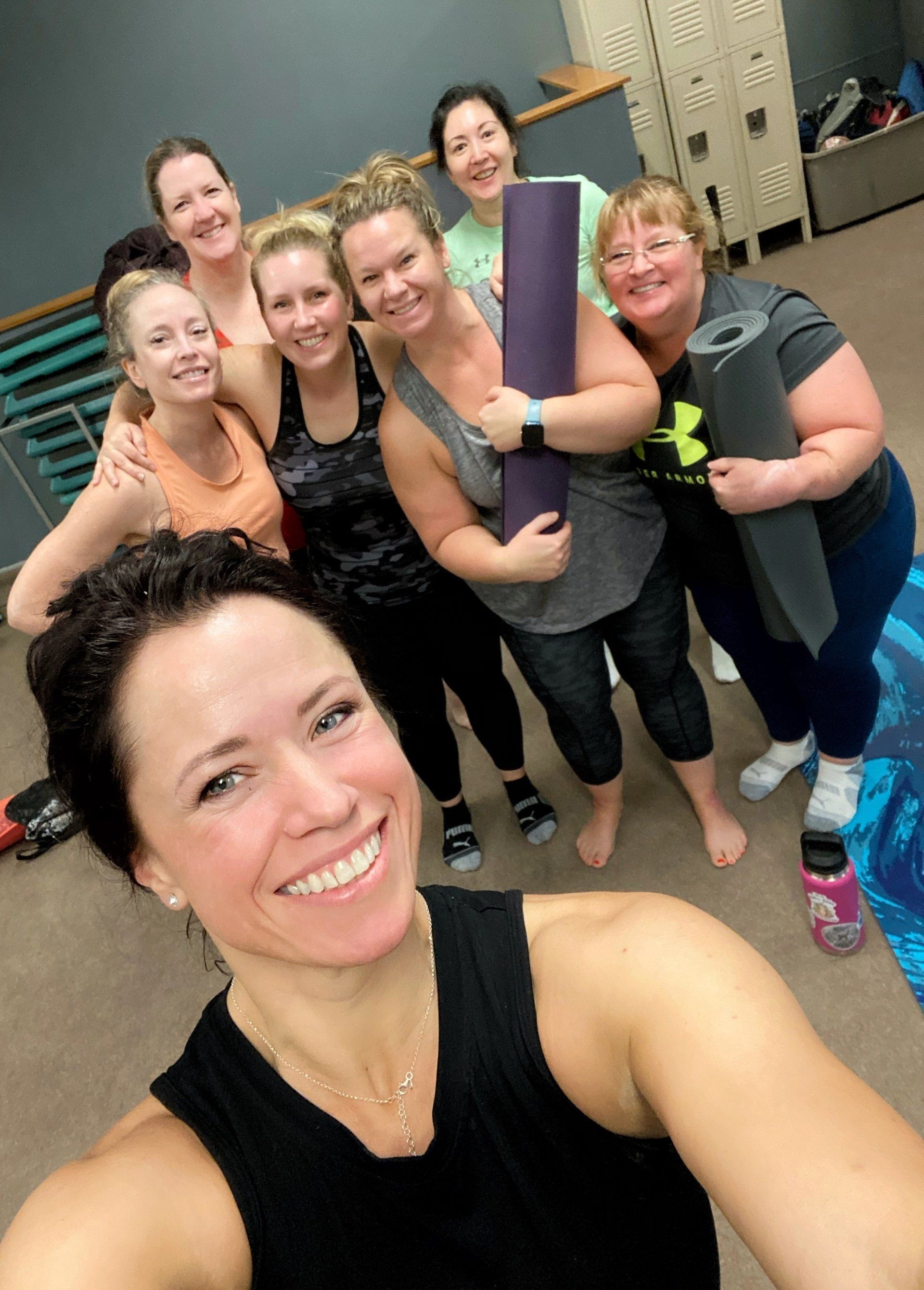 A group of women are posing for a selfie while holding yoga mats