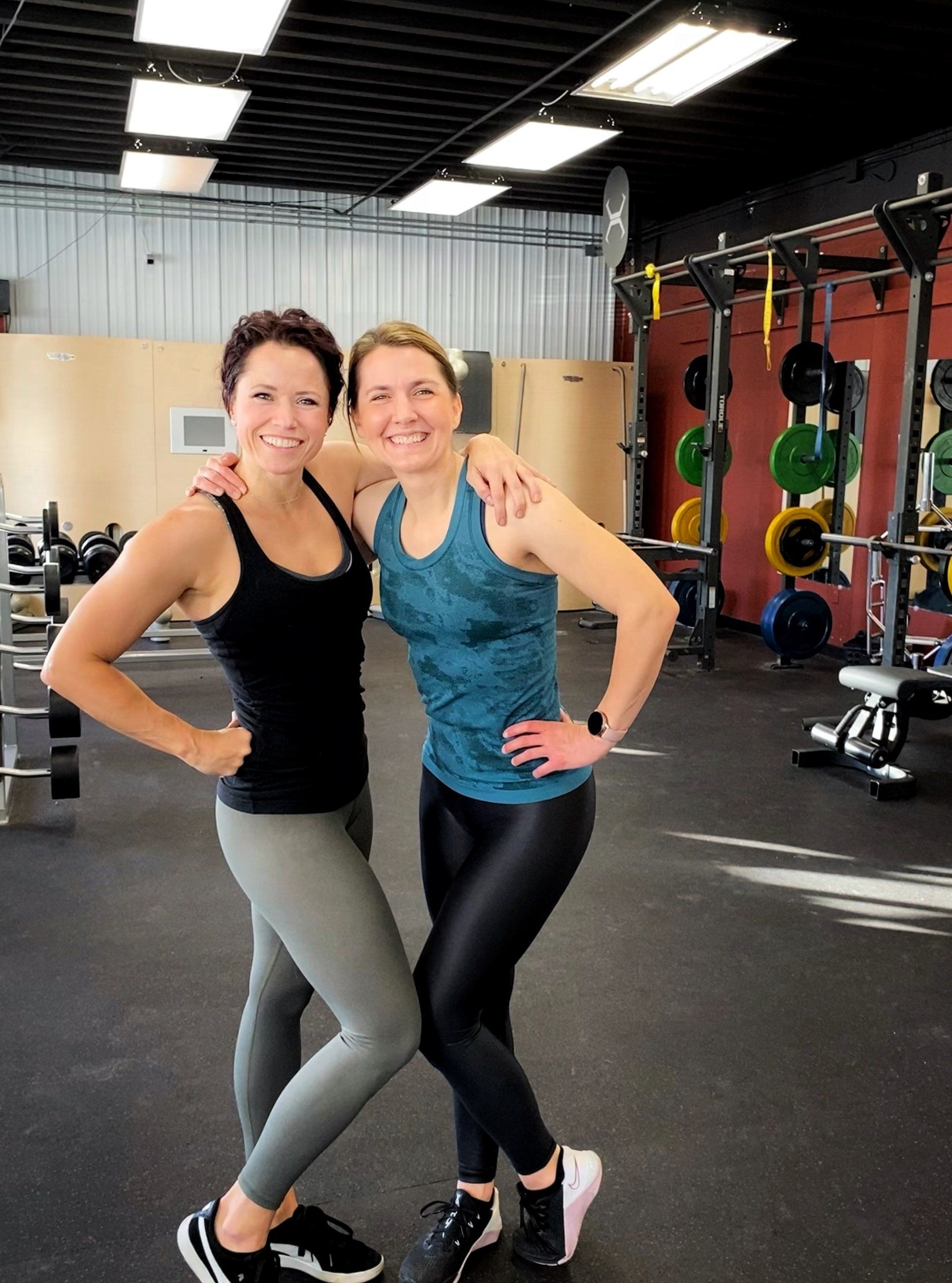 Two women are posing for a picture in a gym