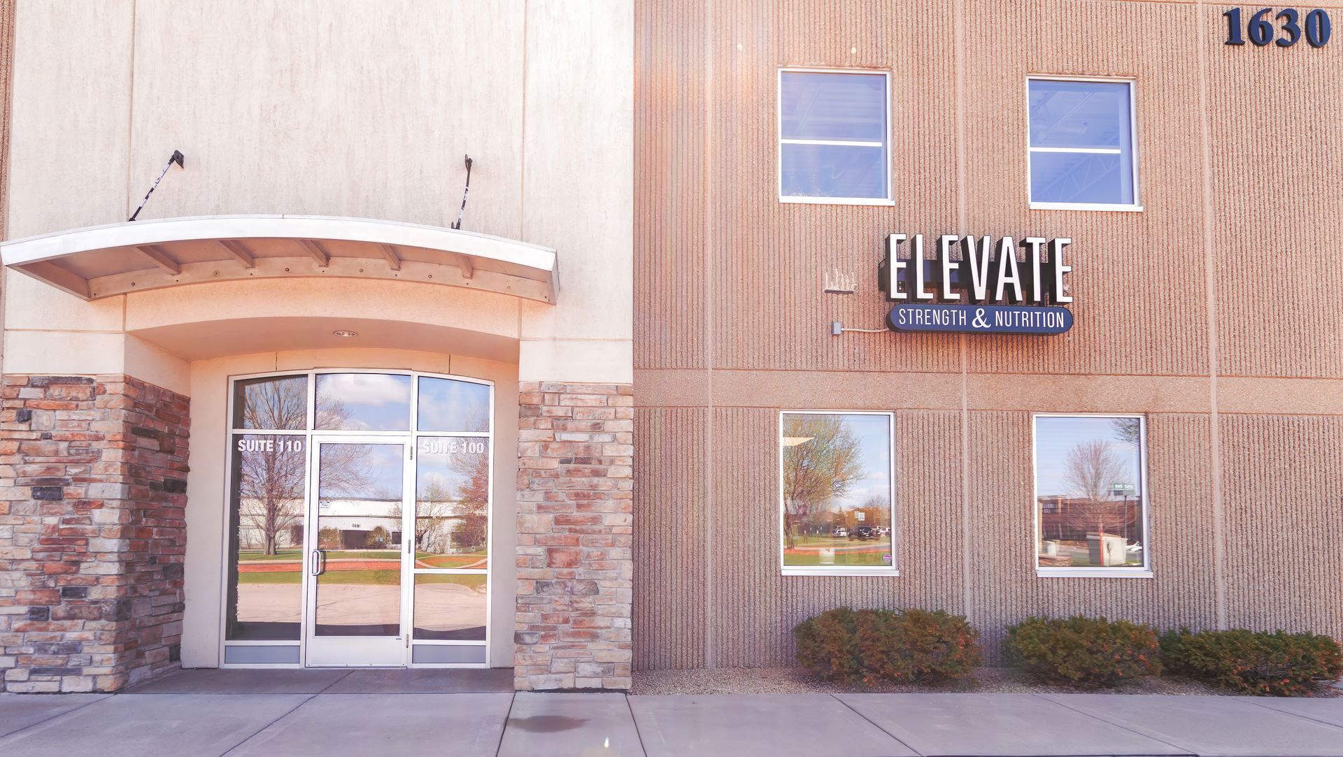 Modern tan office building with glass entrance.