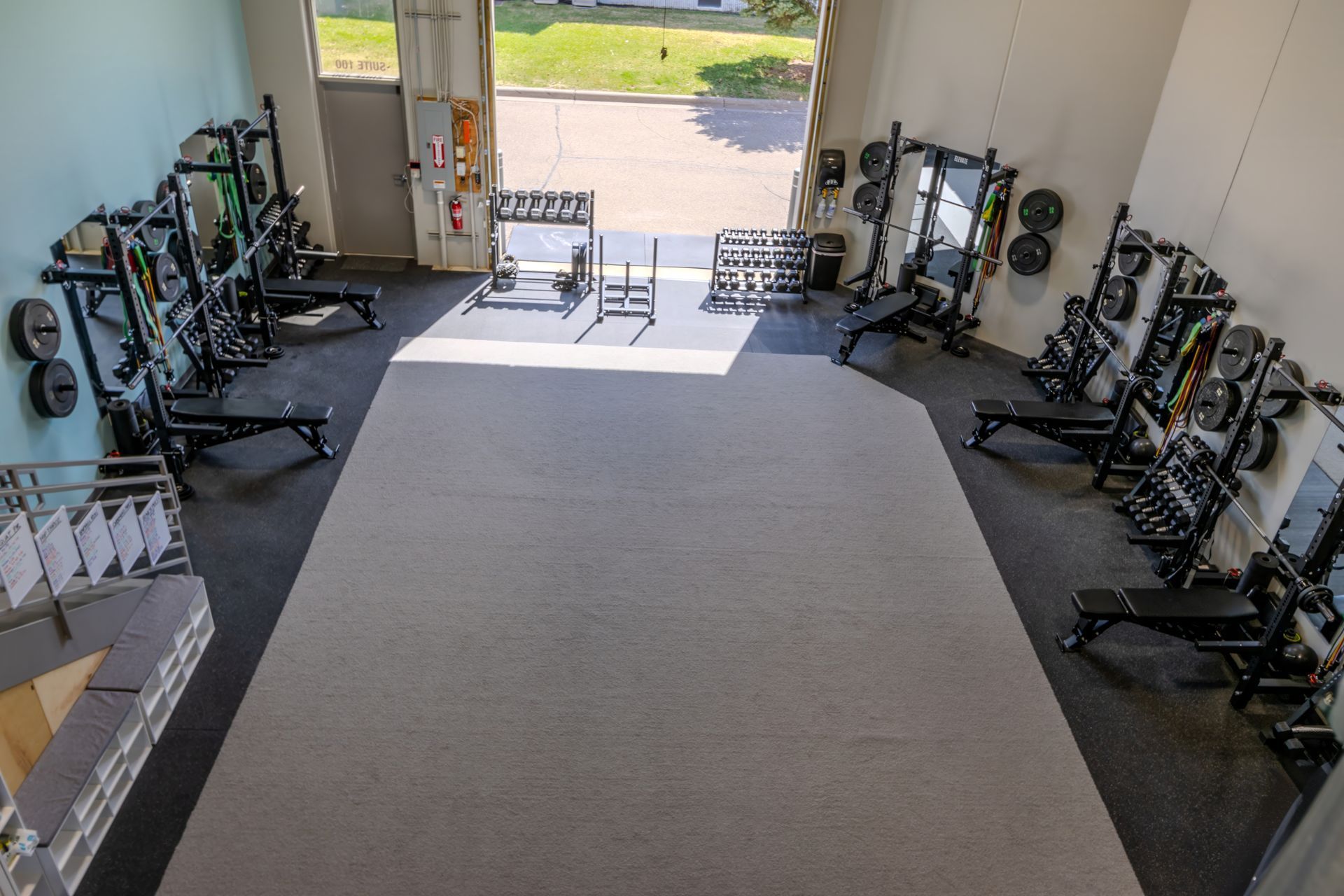 Home gym with rows of weight equipment along the walls and a large exercise mat in the center.