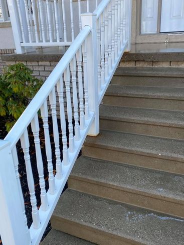 Front steps with concrete stairs and white railing leading to a porch entrance