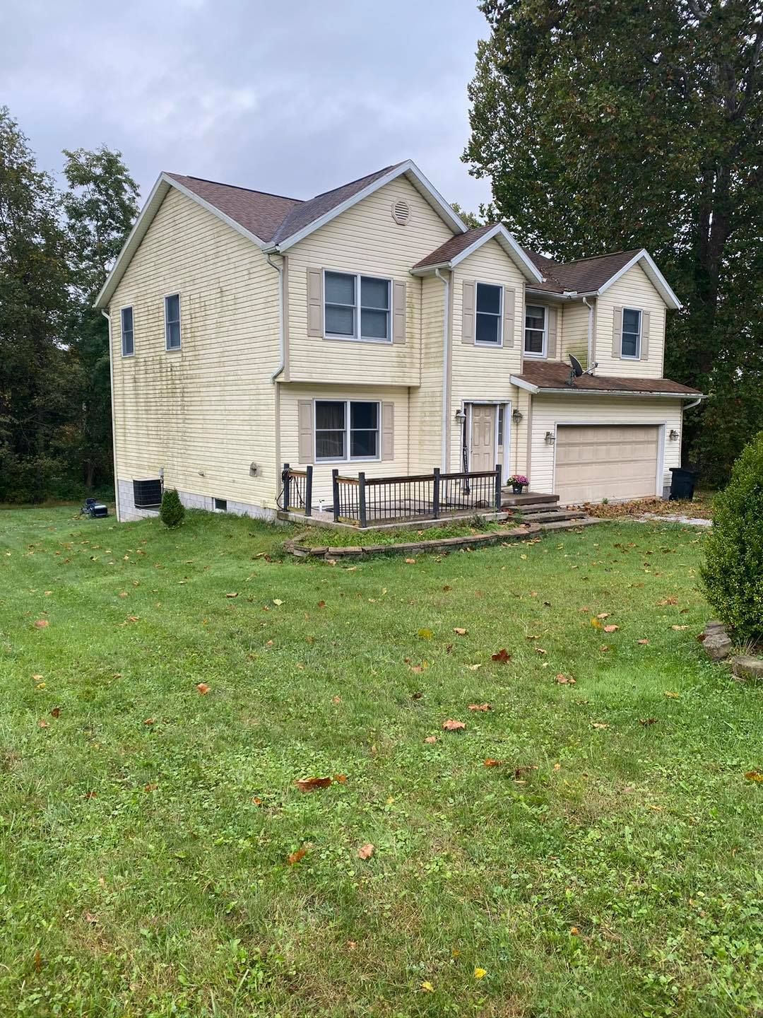Two-story beige house with attached garage and small front porch on a grassy lot