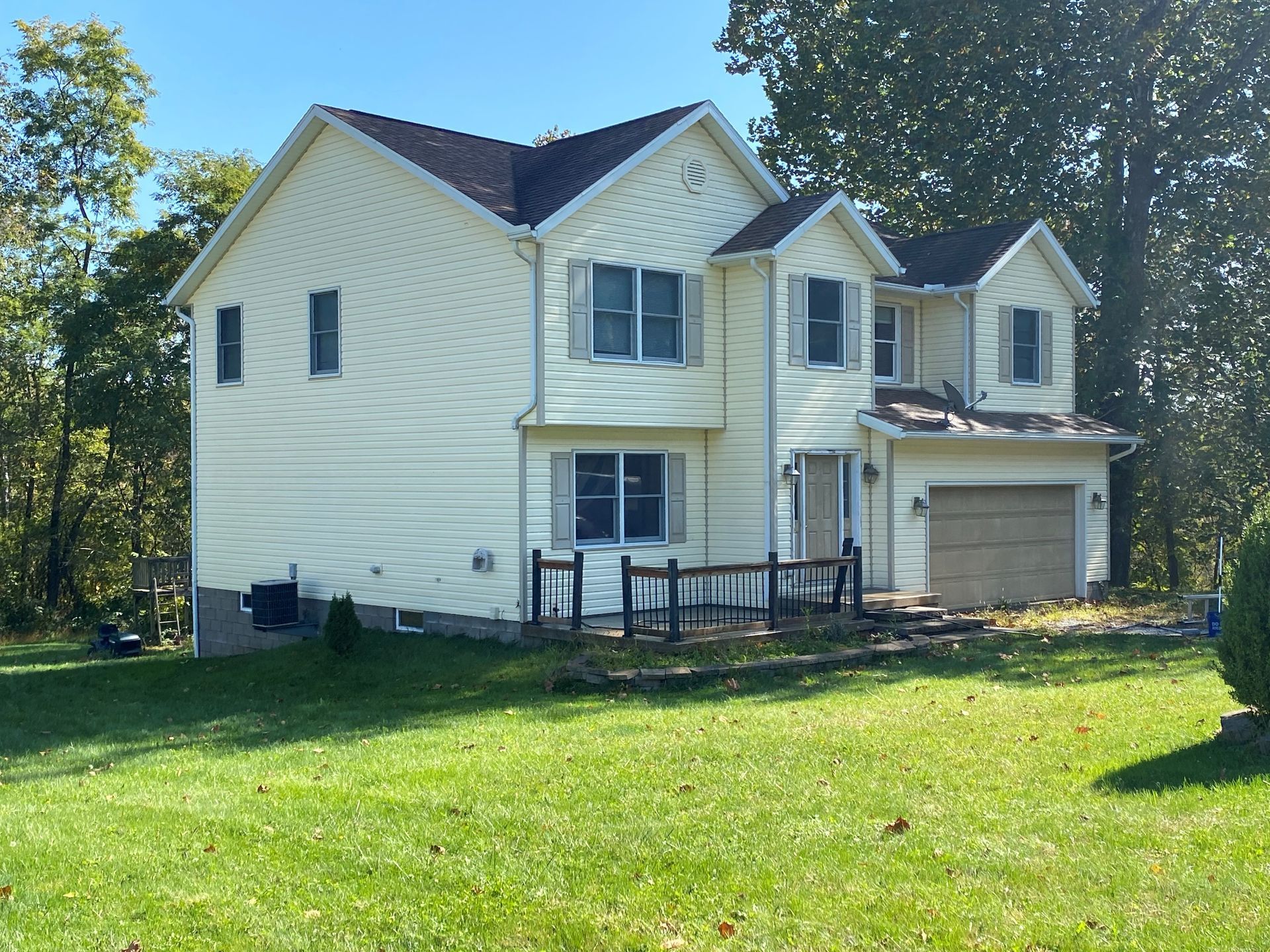 Two-story white suburban house with attached garage and green lawn on a sunny day