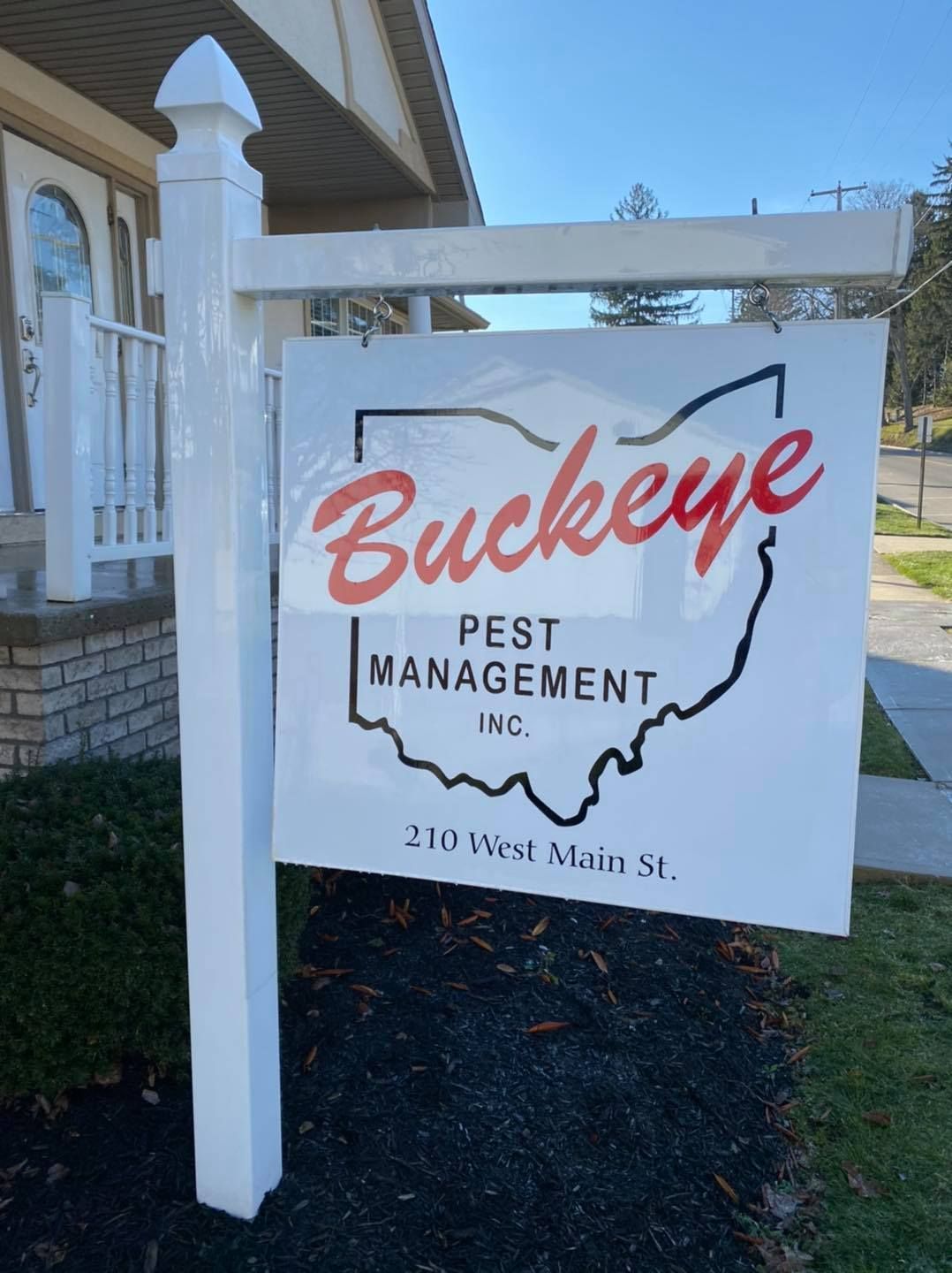 Buckeye Best Management sign hanging on a white post outside, with 210 West Main St. underneath.