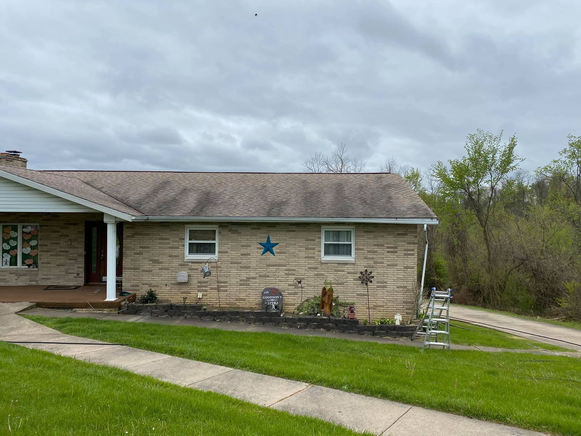 Small brick house with a blue star on the wall, front lawn, and cloudy sky.