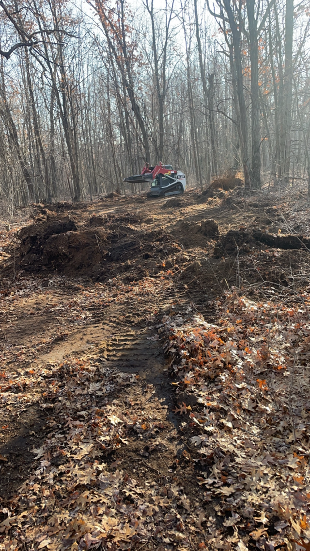ATV on a muddy forest trail with bare trees in the background