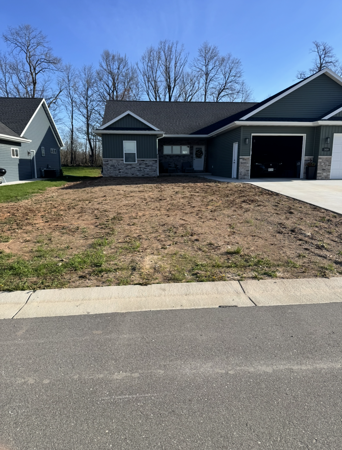 New house with a bare front yard and driveway beside a quiet residential street