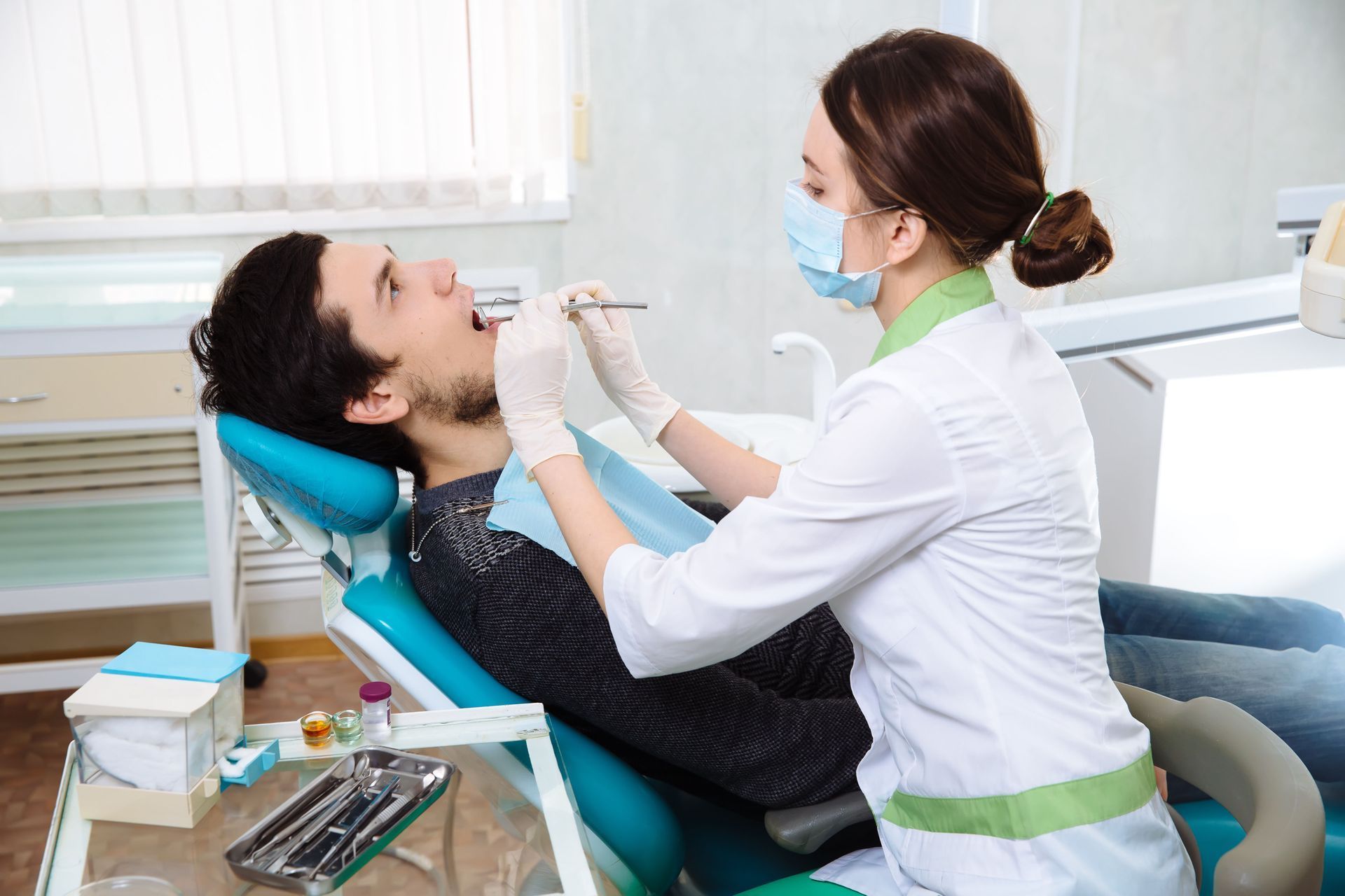 Dentist examining a patient in a bright dental clinic, with tools on a tray nearby