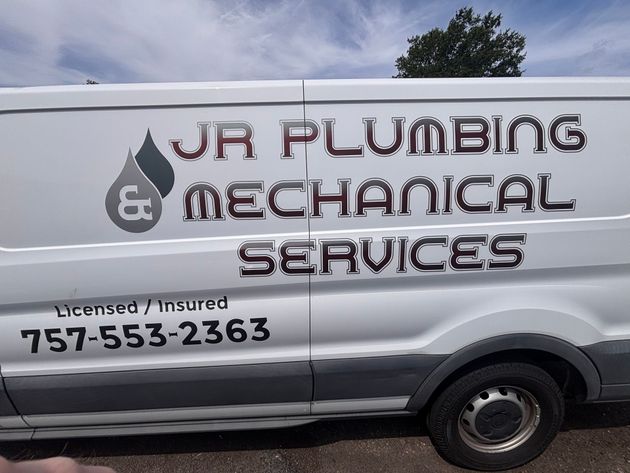 White JR Plumbing & Mechanical Services van with phone number parked outdoors under a cloudy sky