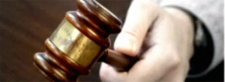 Hand holding a wooden gavel, symbolizing a court ruling