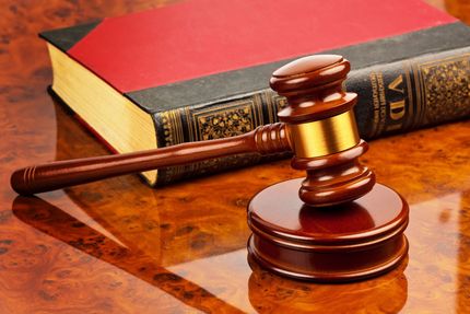 Wooden gavel beside law books on a polished desk