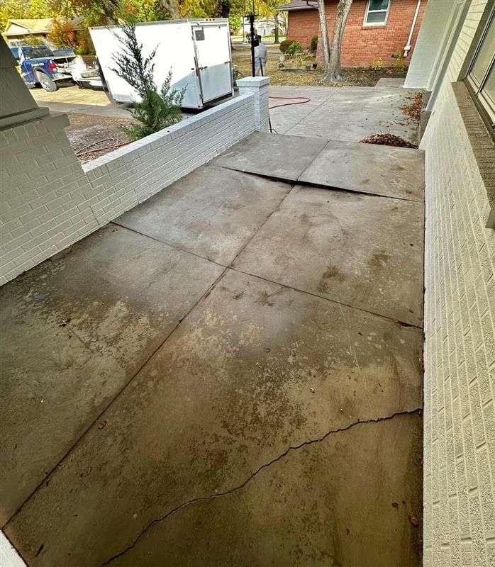 A concrete porch with a brick wall and a white trailer parked in the background.