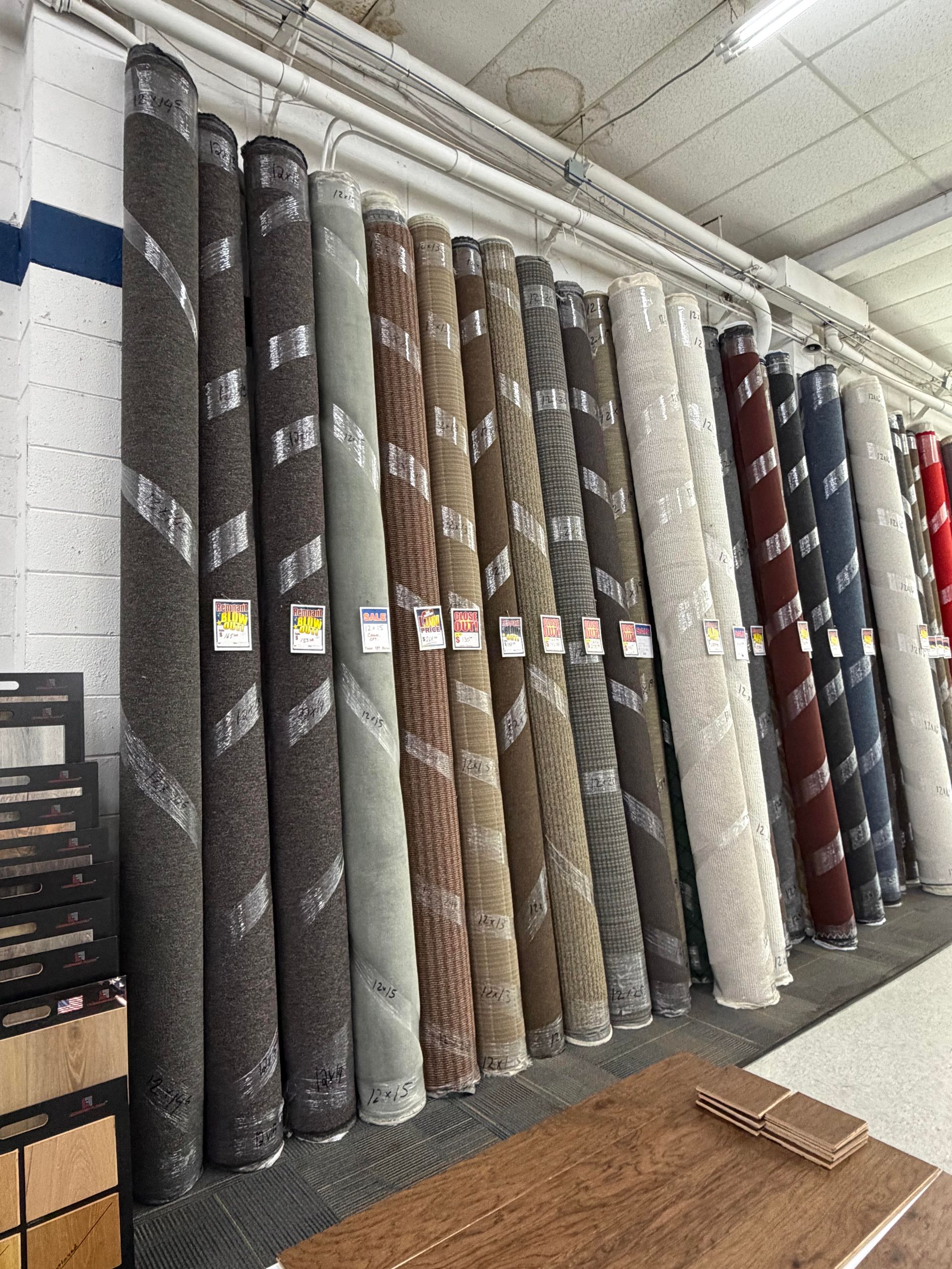 Rolled carpet samples displayed upright in a store showroom under bright lights