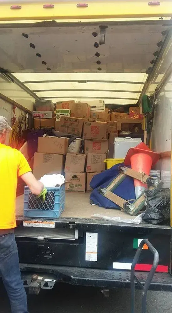 Person loading boxes into a moving truck. Interior view with a full load of boxes and other items.