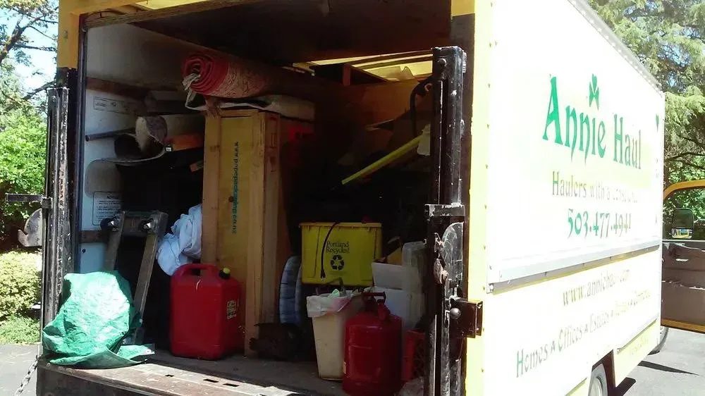Open rear of Annie Haul truck filled with items like a red gas can and furniture.