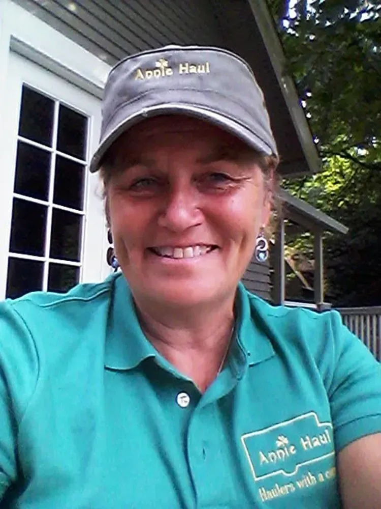 Woman in green shirt and hat smiling, 