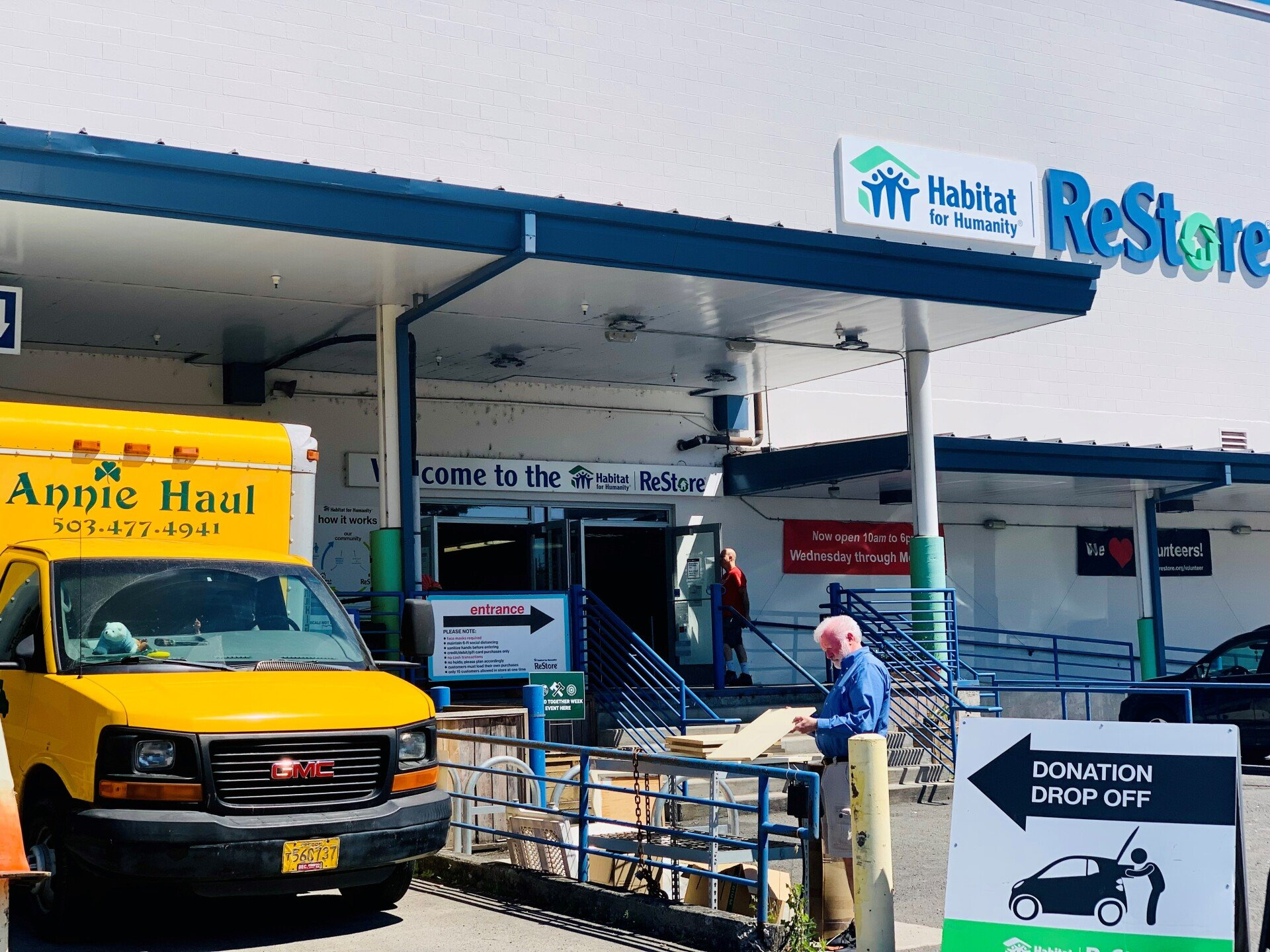 Exterior of Habitat for Humanity ReStore store with a donation drop-off sign and Annie Haul truck.