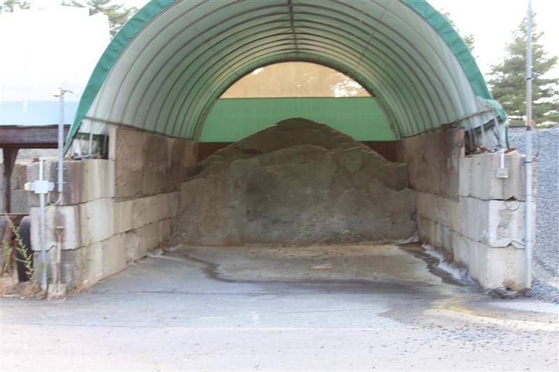 Storage shed with a large pile of gray gravel.