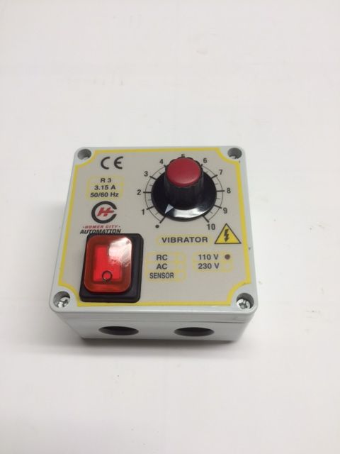 Small white vibration controller box with a red switch and black-red dial on top.