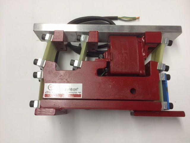 Red and silver metal industrial machine component with attached cable, viewed from above.