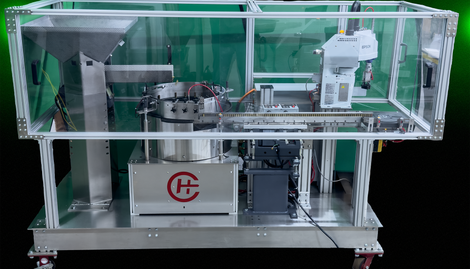 Automated industrial machine enclosed in a clear safety guard on a wheeled metal frame