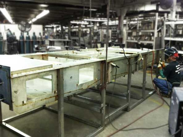 A man is welding a piece of metal in a factory.