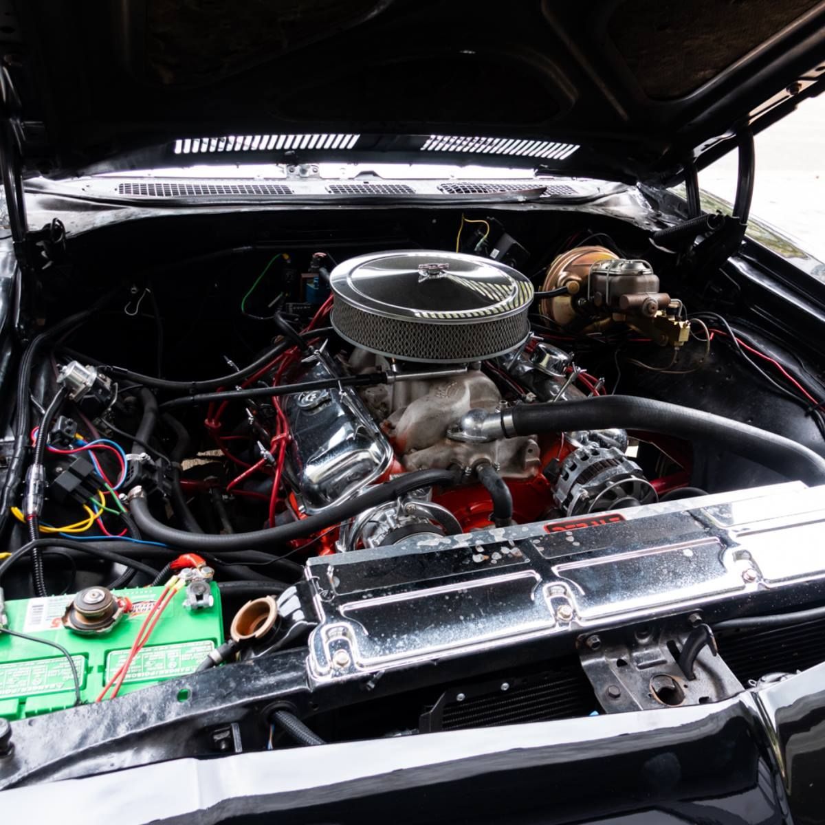 Black car engine with chrome details and red wiring.