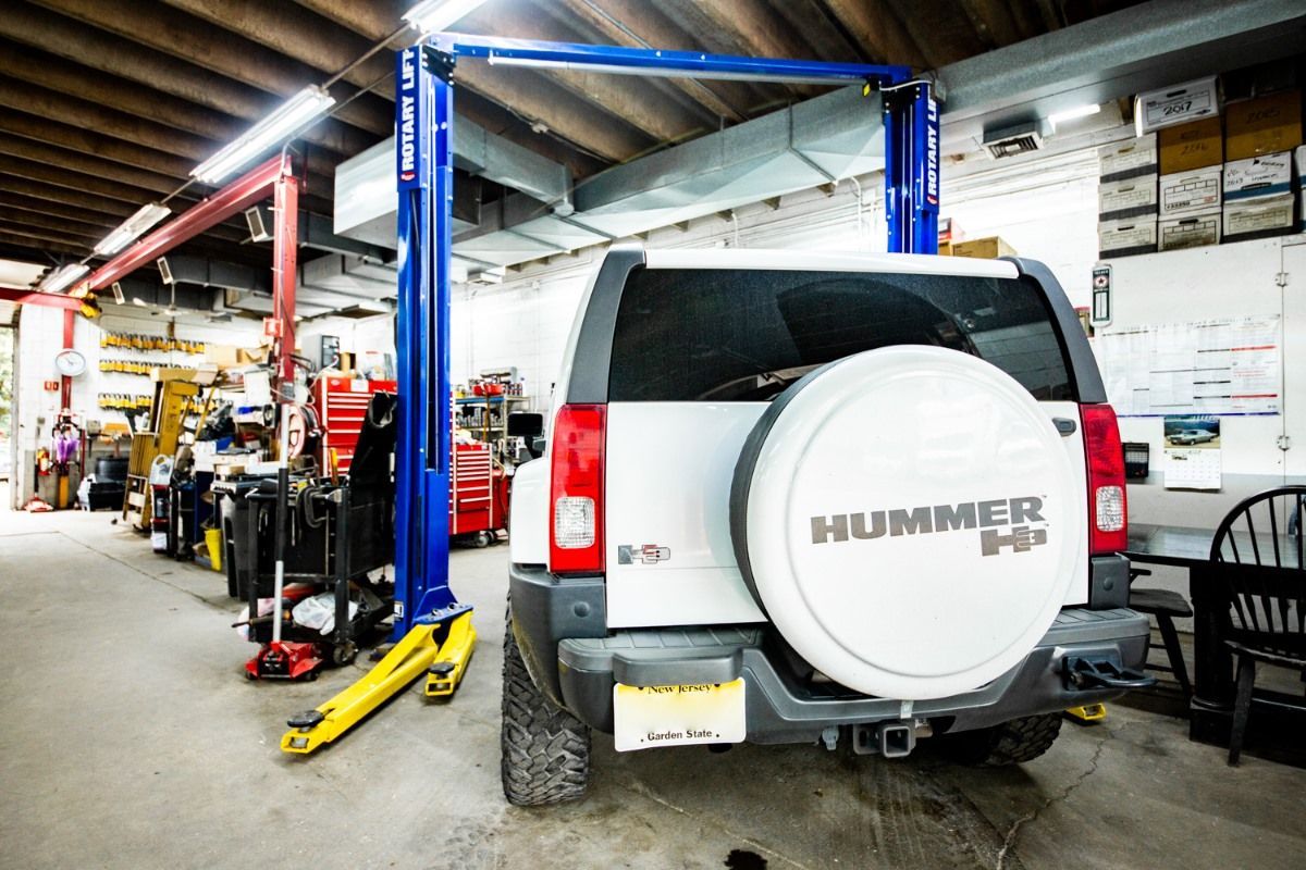 Black classic car engine compartment with chrome and red components. Hood open.