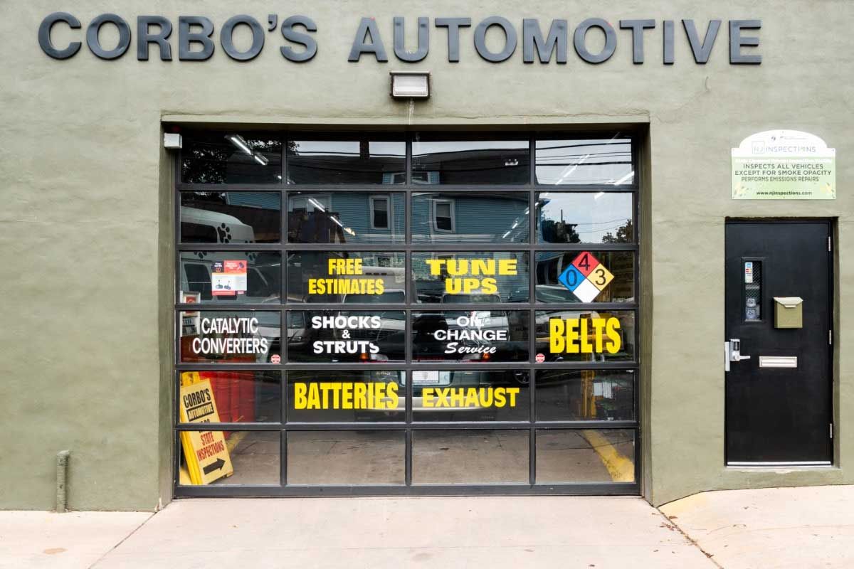 Corbo's Automotive building with glass garage door advertising auto repair services, black trim, and green walls.