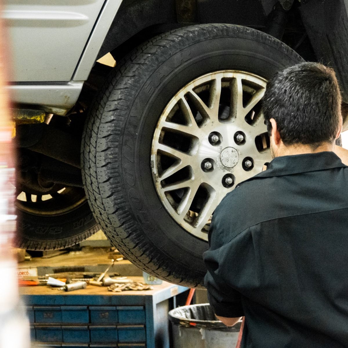 Mechanic working on a car tire in a garage.