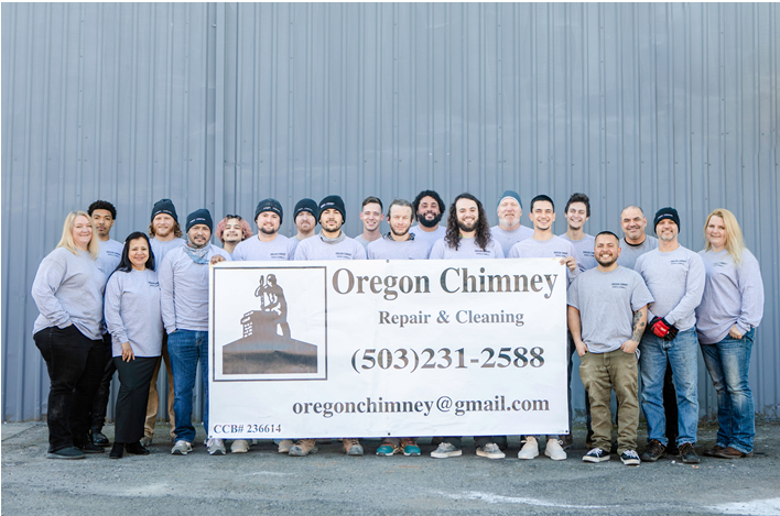 Group of people posing behind an Oregon Chimney banner in front of a metal wall.