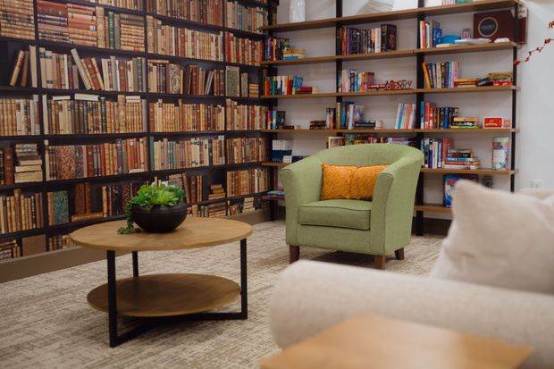 A cozy reading nook with bookshelves, green armchair, round coffee table, and sofa.
