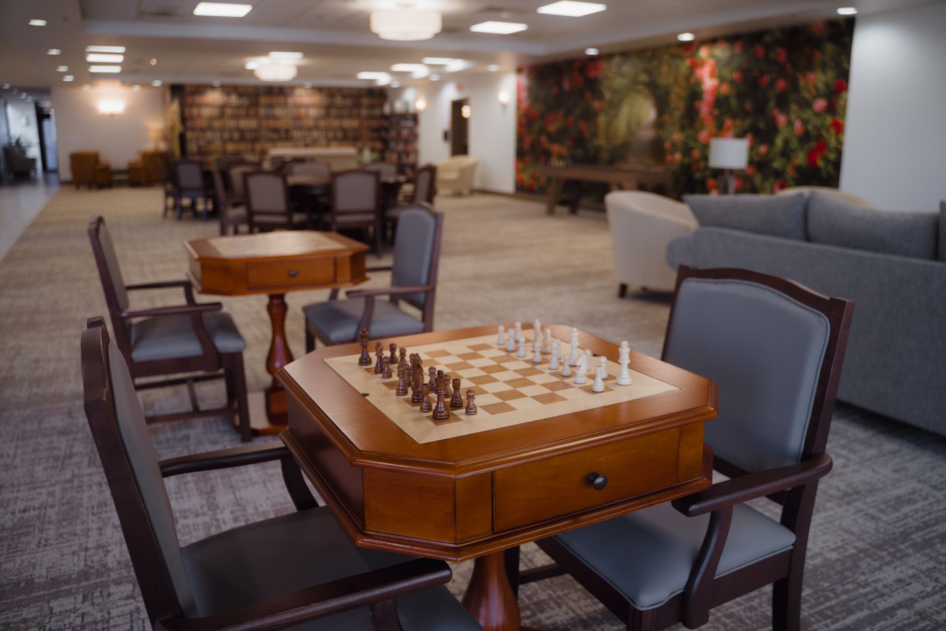 Chess table with pieces set up, surrounded by chairs in a lounge area.