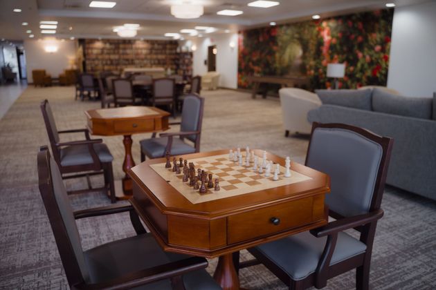 Chess table with pieces set up, surrounded by chairs in a lounge area.