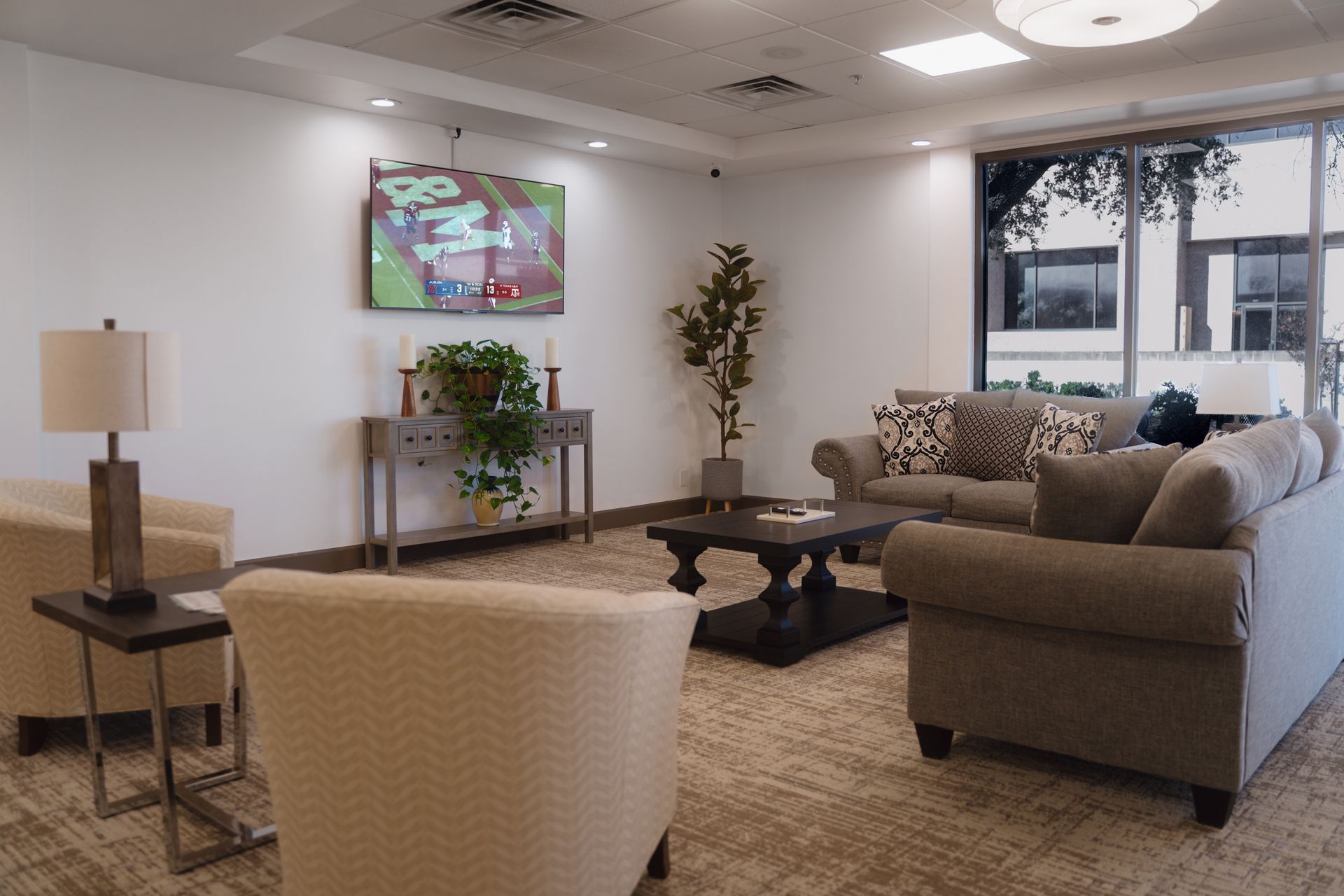 Cozy living room with seating, a coffee table, and a TV; large window provides natural light.