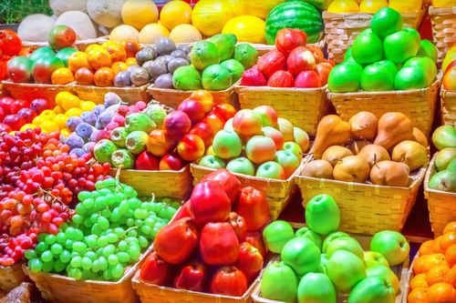 Colorful display of various fruits in wicker baskets at a market.