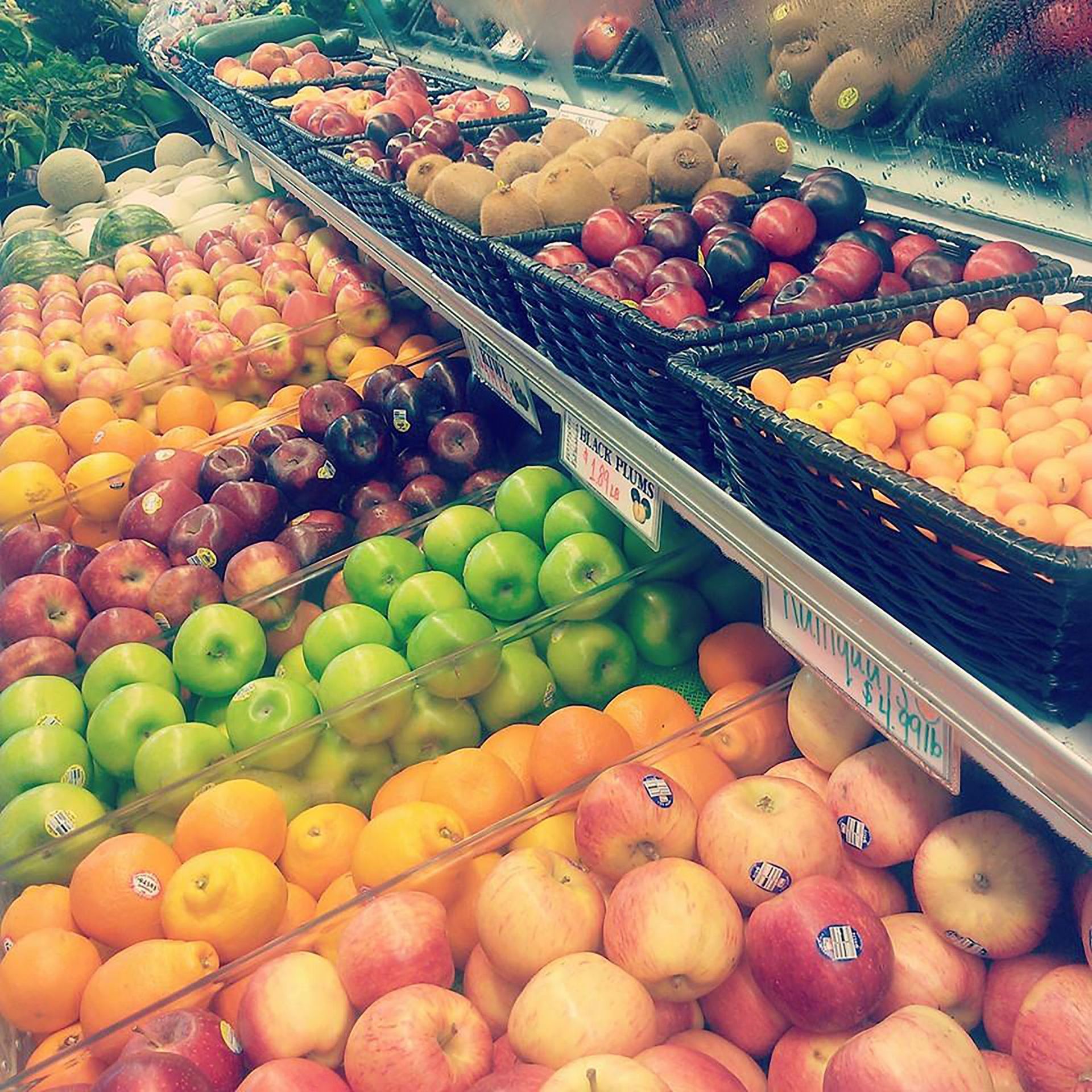A produce section at a grocery store with a variety of colorful fruits including apples, oranges, and kiwis.