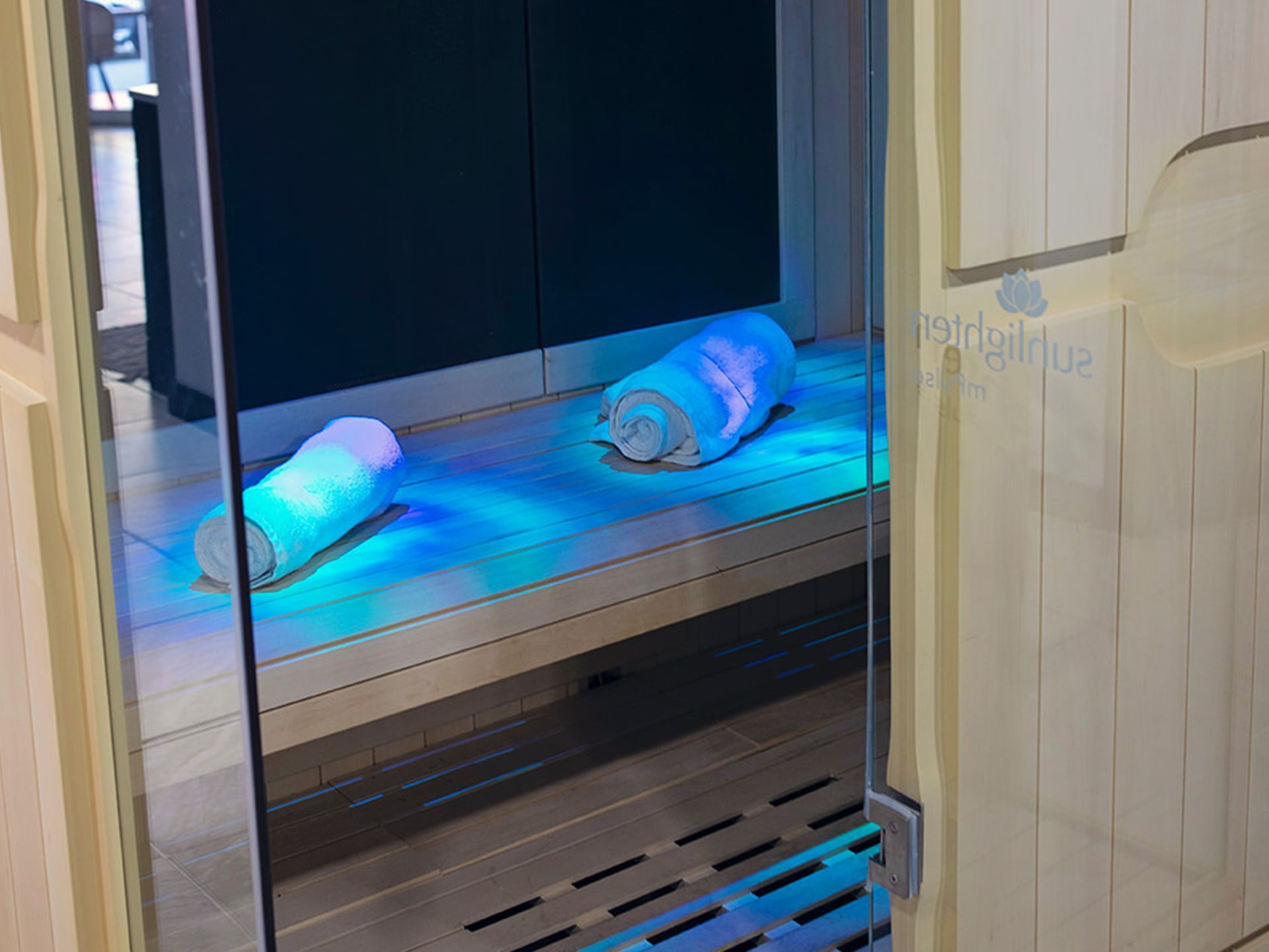 Sauna interior with towels illuminated by blue and purple lights.