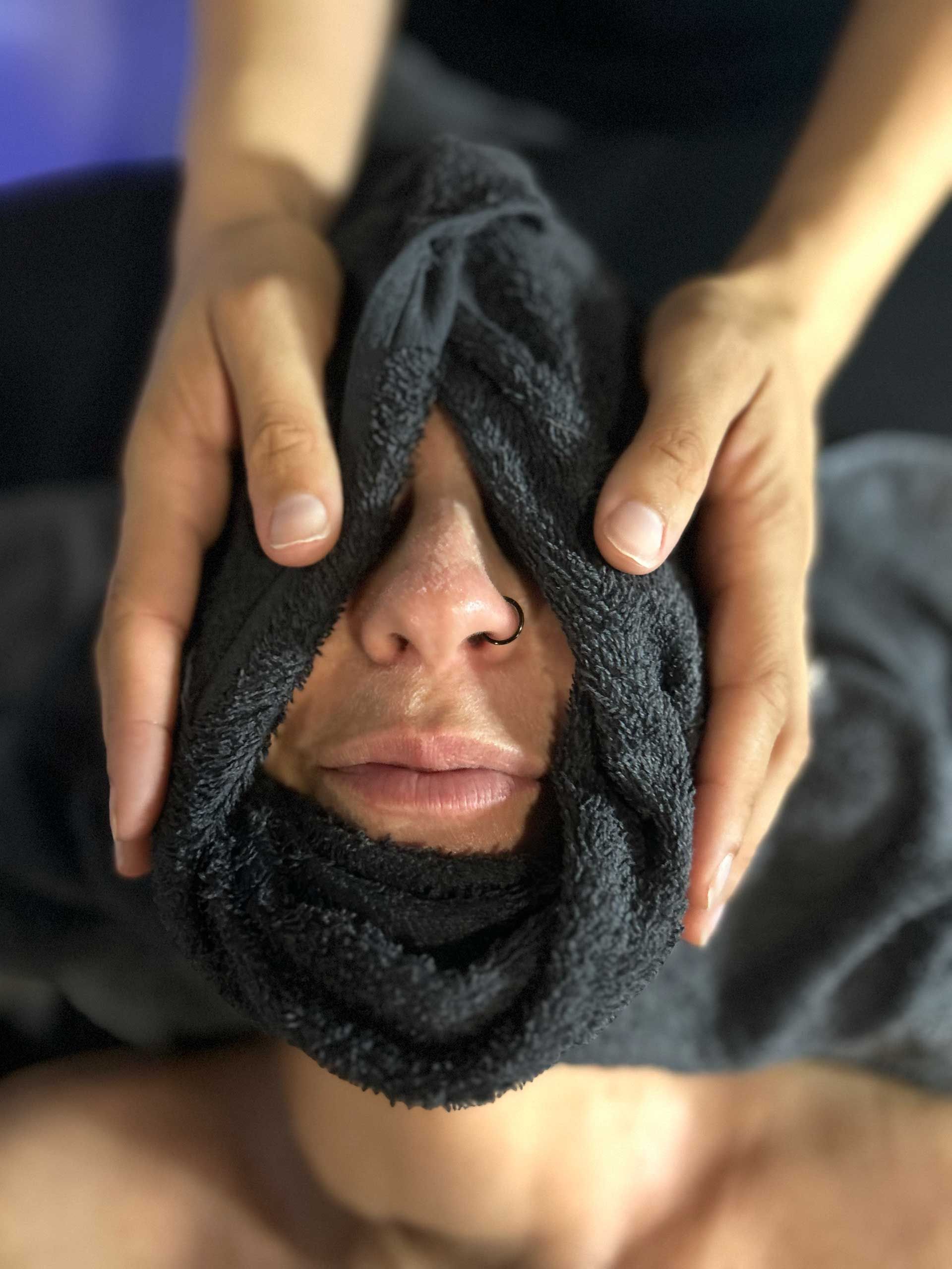person's face covered with a black towel, hands around head