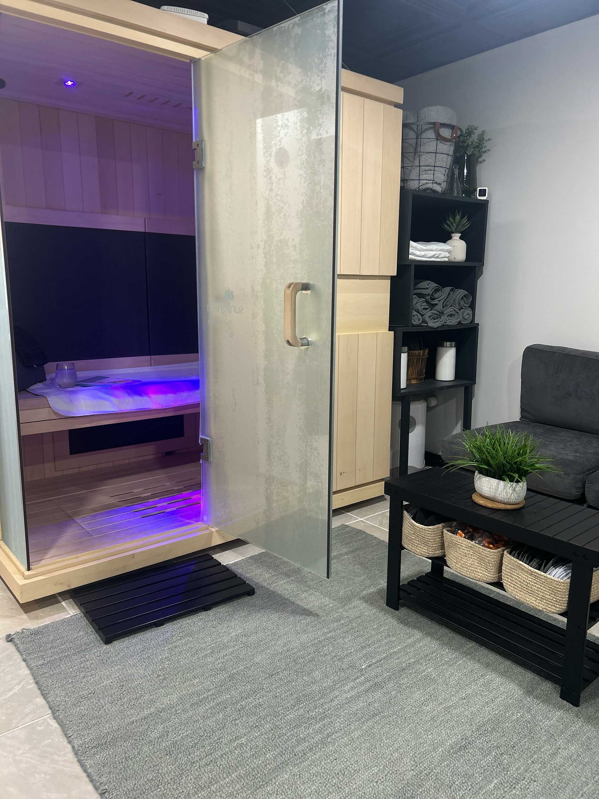 sauna with glass door, small seating area, and storage shelves