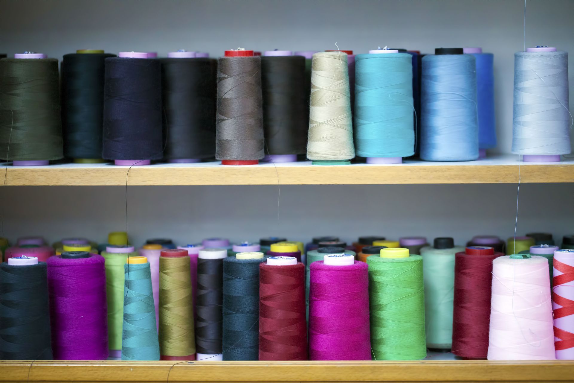 Two shelves filled with spools of thread of different colors