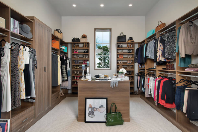 A large walk in closet filled with clothes and a desk