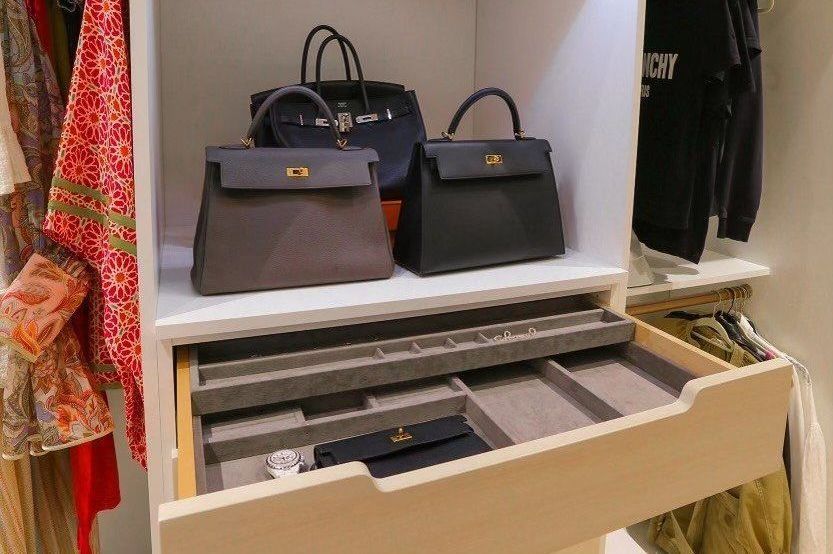 Two handbags are sitting on top of a shelf in a closet.