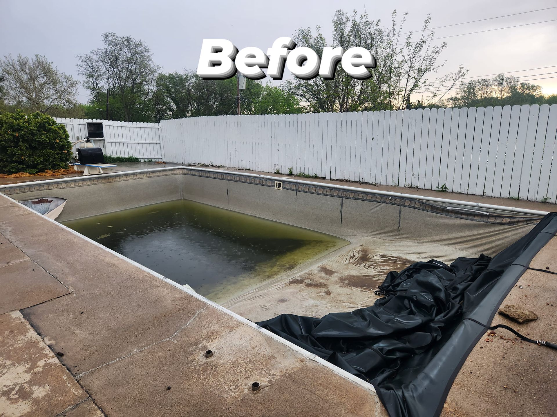 A before picture of a swimming pool with a white fence