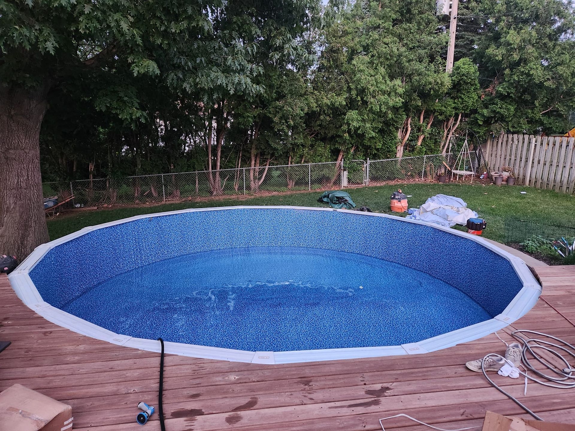 A round swimming pool is being built in a backyard.ayward