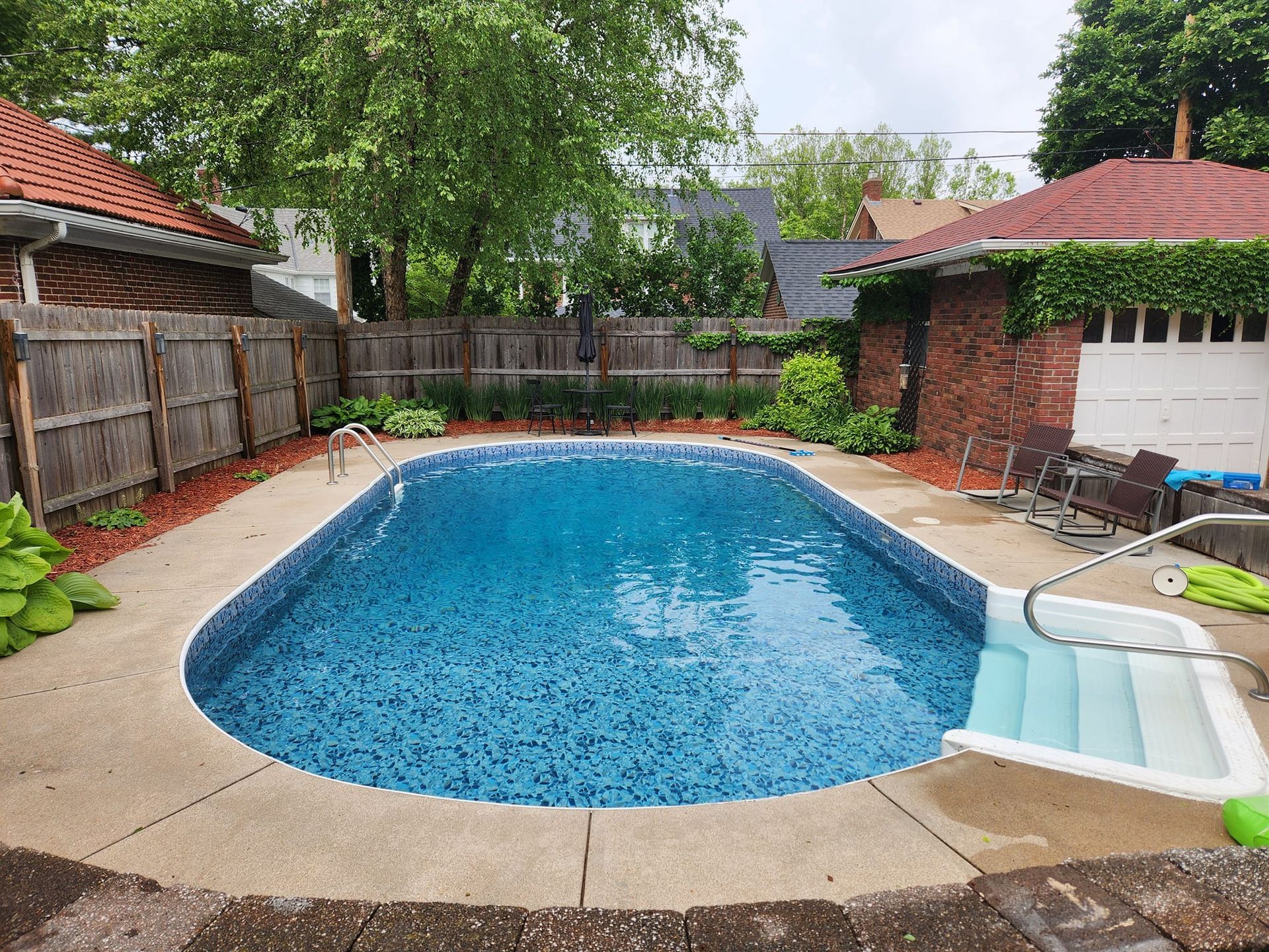 There is a large swimming pool in the backyard of a house.