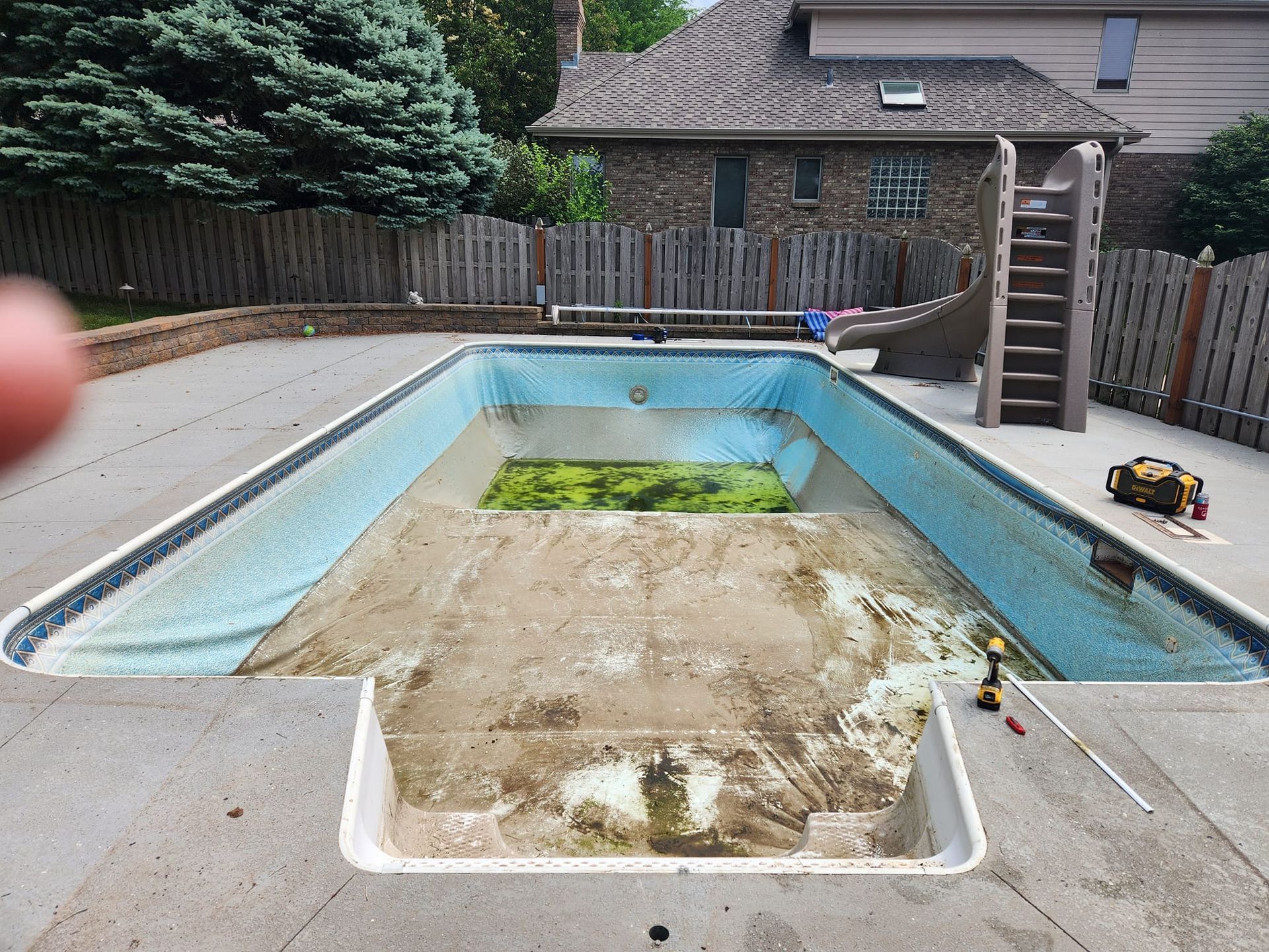 An empty swimming pool with a house in the background