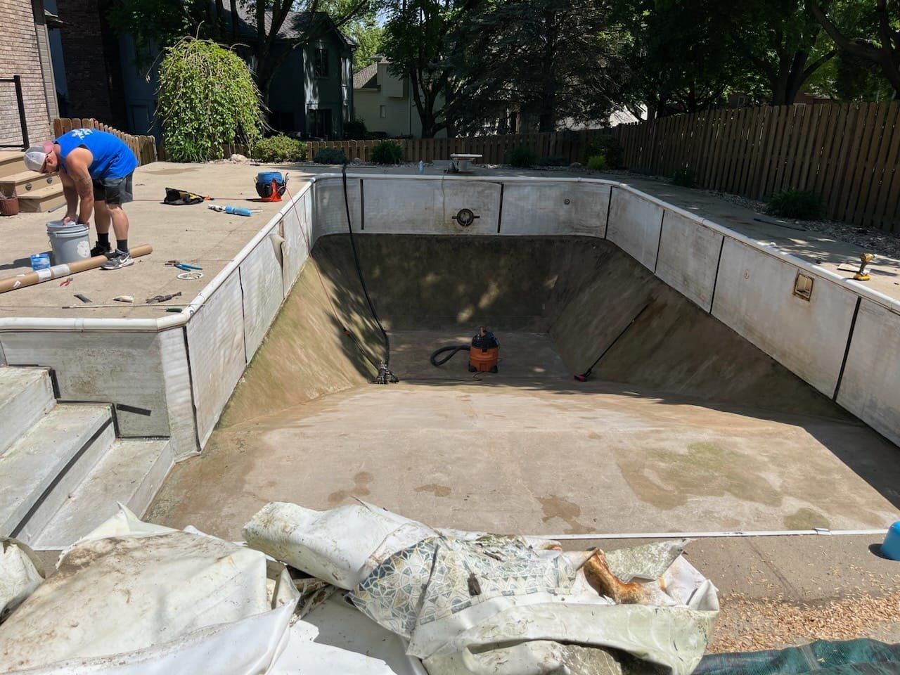 A man is working on a swimming pool in a backyard.
