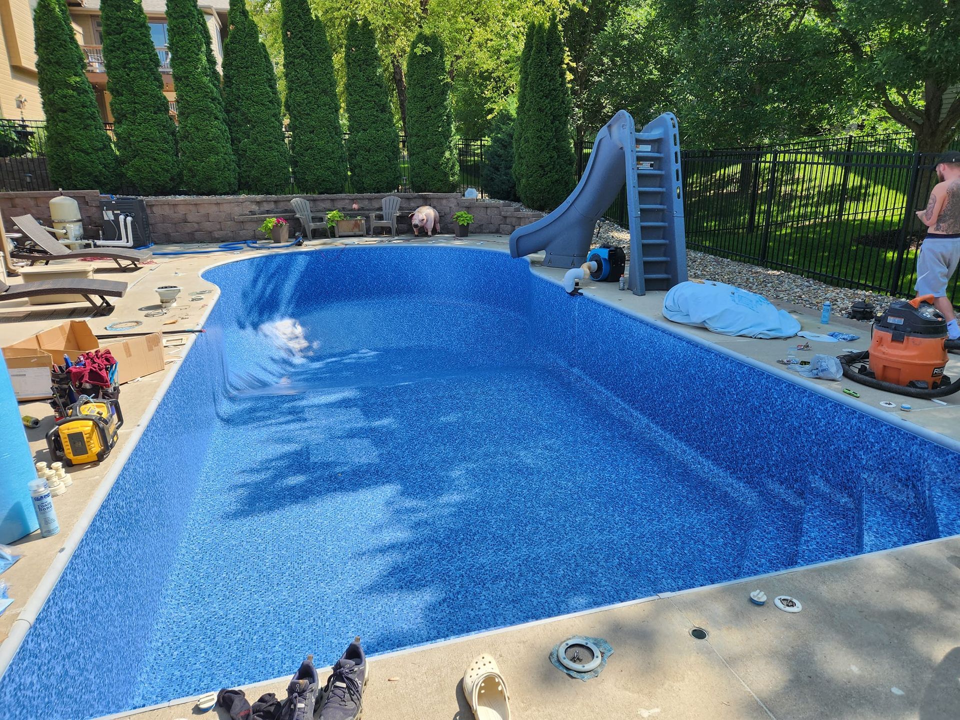 A large blue swimming pool with a slide in the backyard.